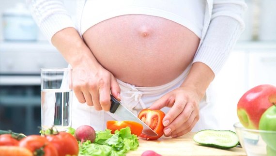 Mujer embarazada preparando ensaladas